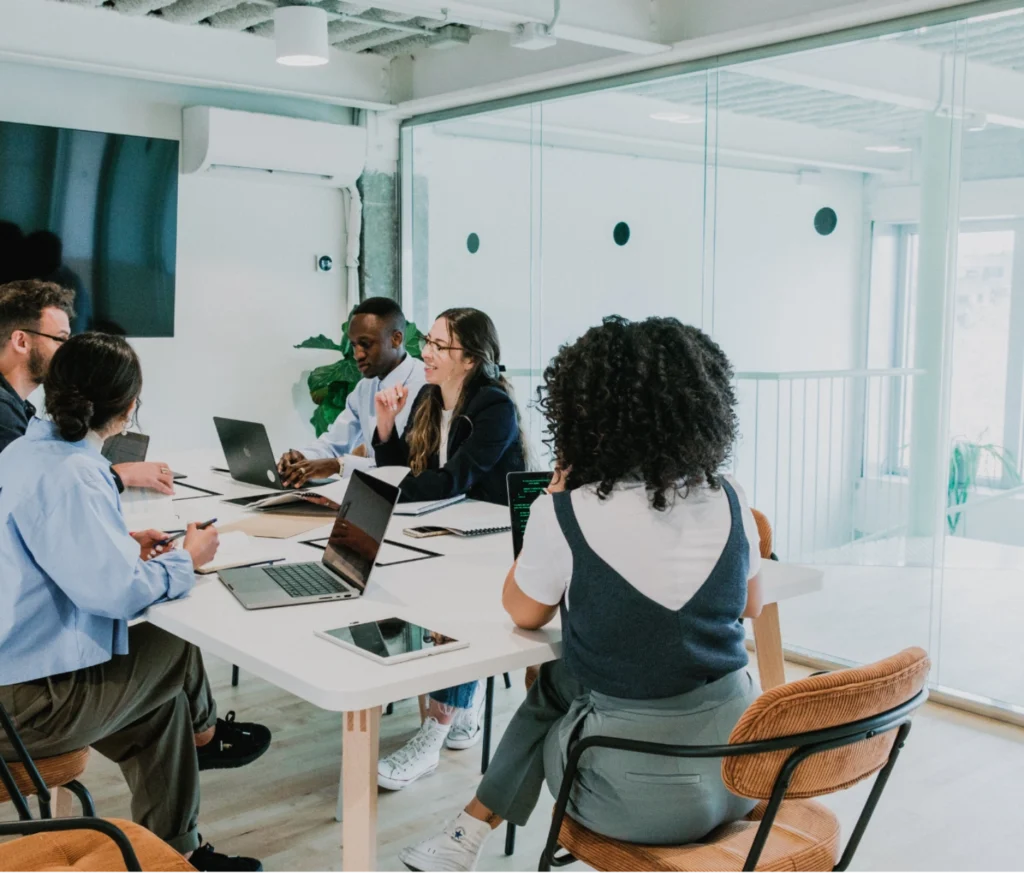 Diverse group of professionals having a team meeting in a modern office with laptops and notebooks
