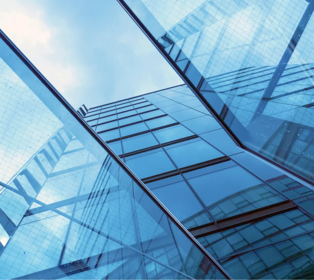 Upward view of a modern glass office building with reflective windows and steel framework