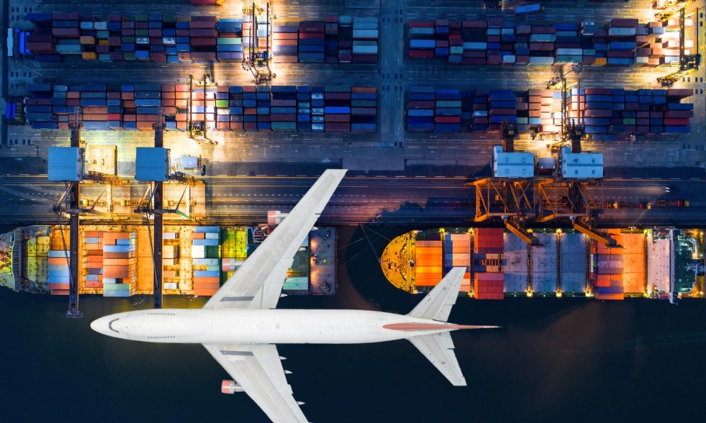 Aeroplane flying over cargo ships at a dock